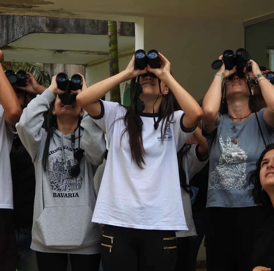 Grupo de estudantes observando aves com binóculos