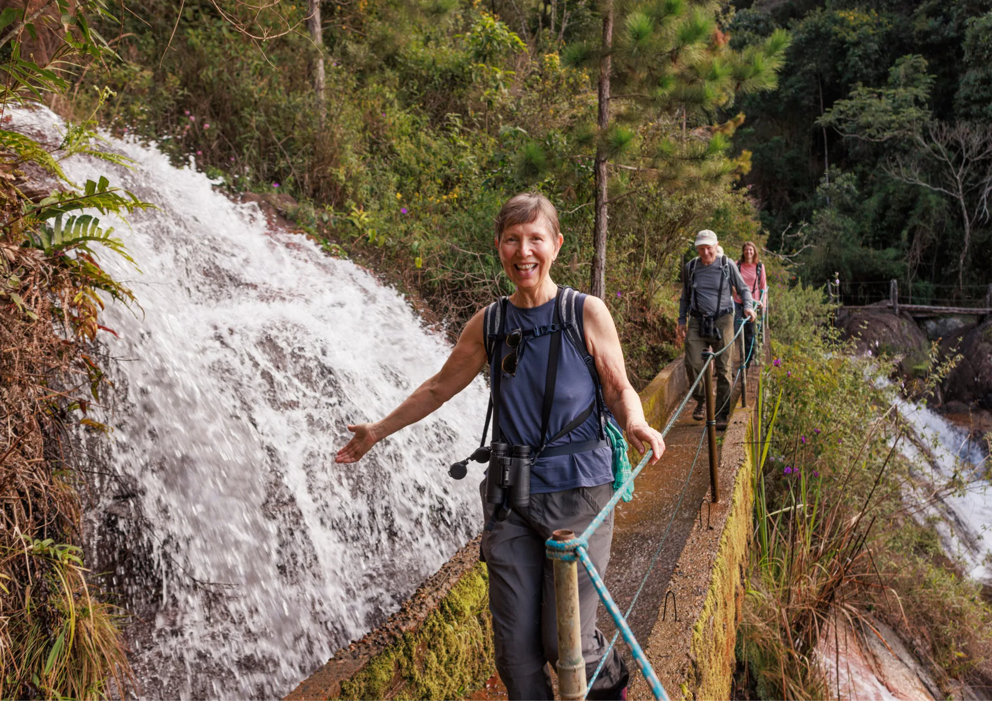 Visitante sorrindo ao lado de cachoeira em trilha durante a Fundraising Field Trip